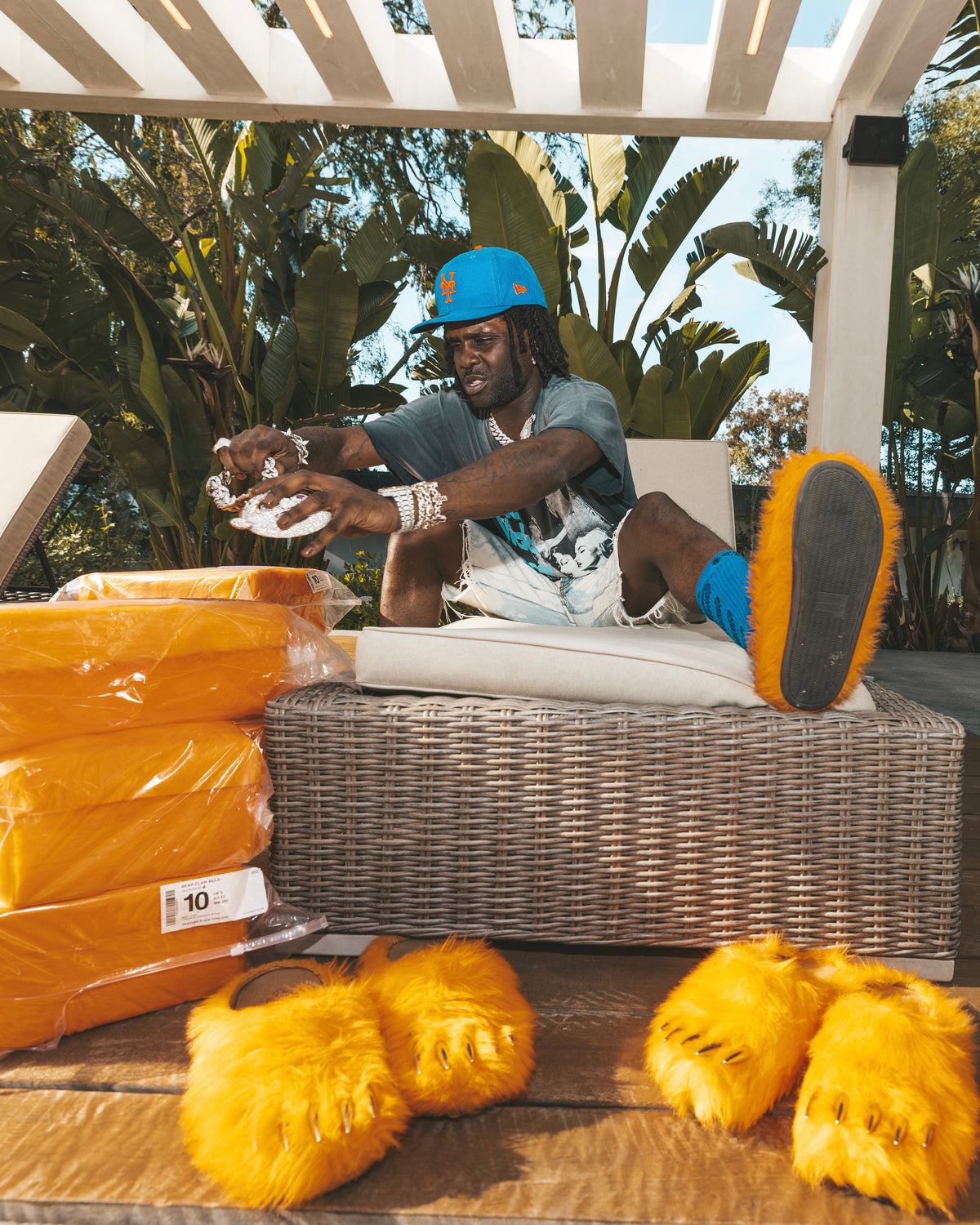 Orange plush bear-claw slippers and packaged pairs on a wicker bench.