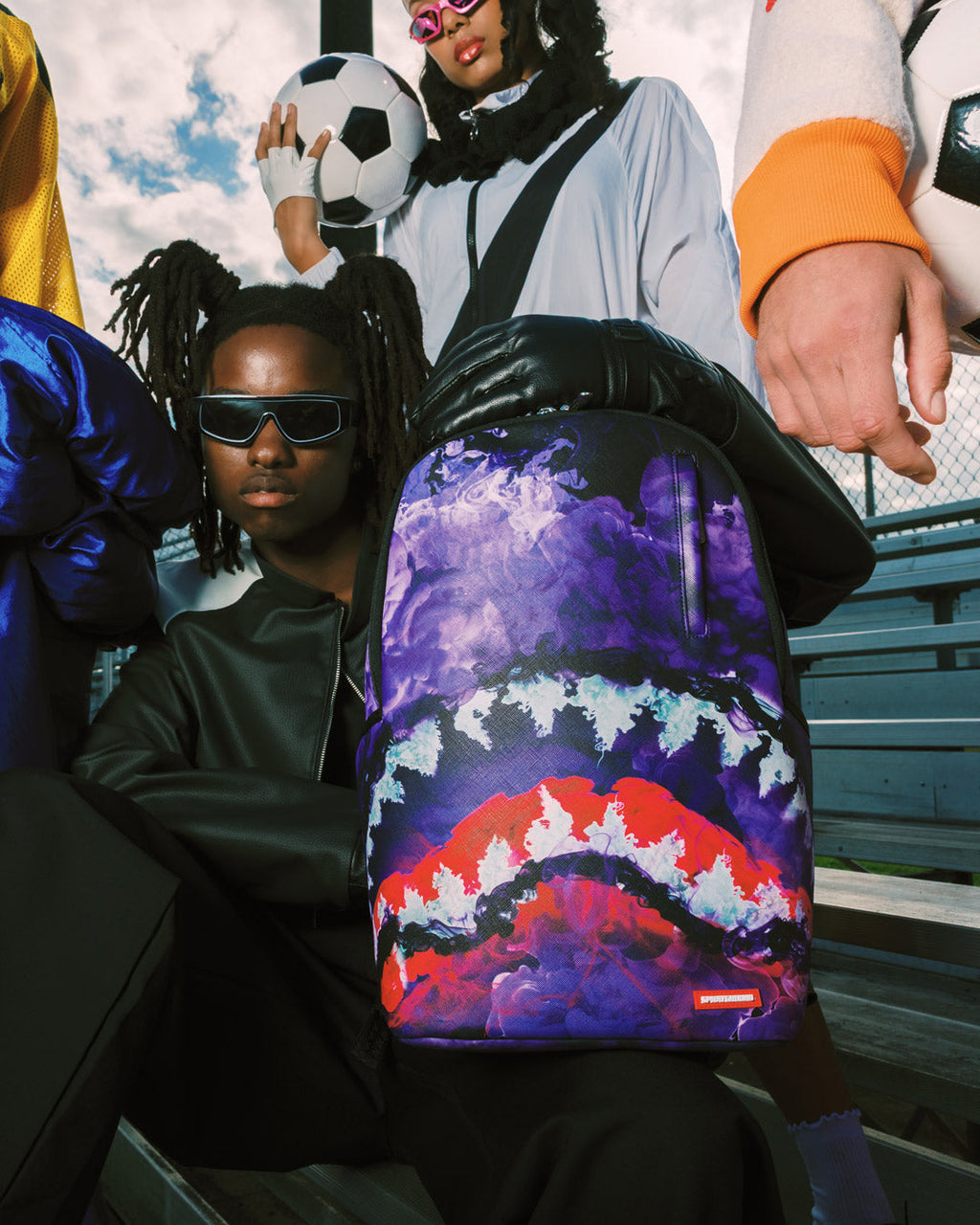 Purple backpack bag with red and white cloud graphic, shown upright with black straps