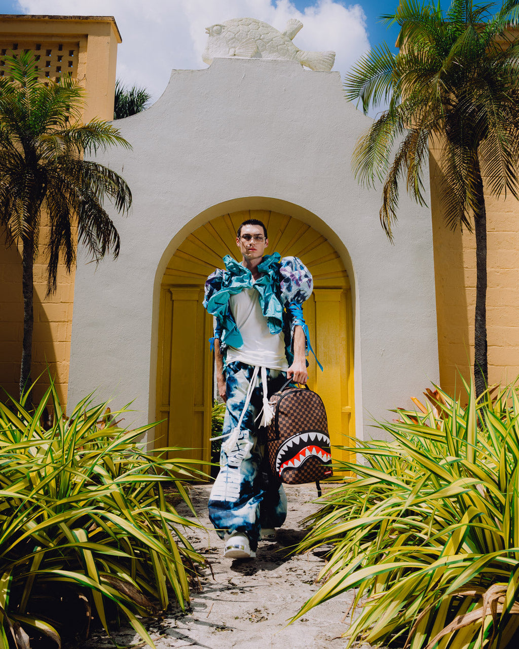 Backpack with shark-mouth graphic on a person in blue patterned outfit