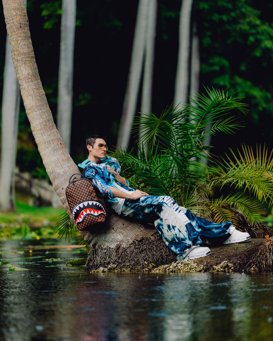 Shark-mouth backpack carried by a person outdoors near greenery and water