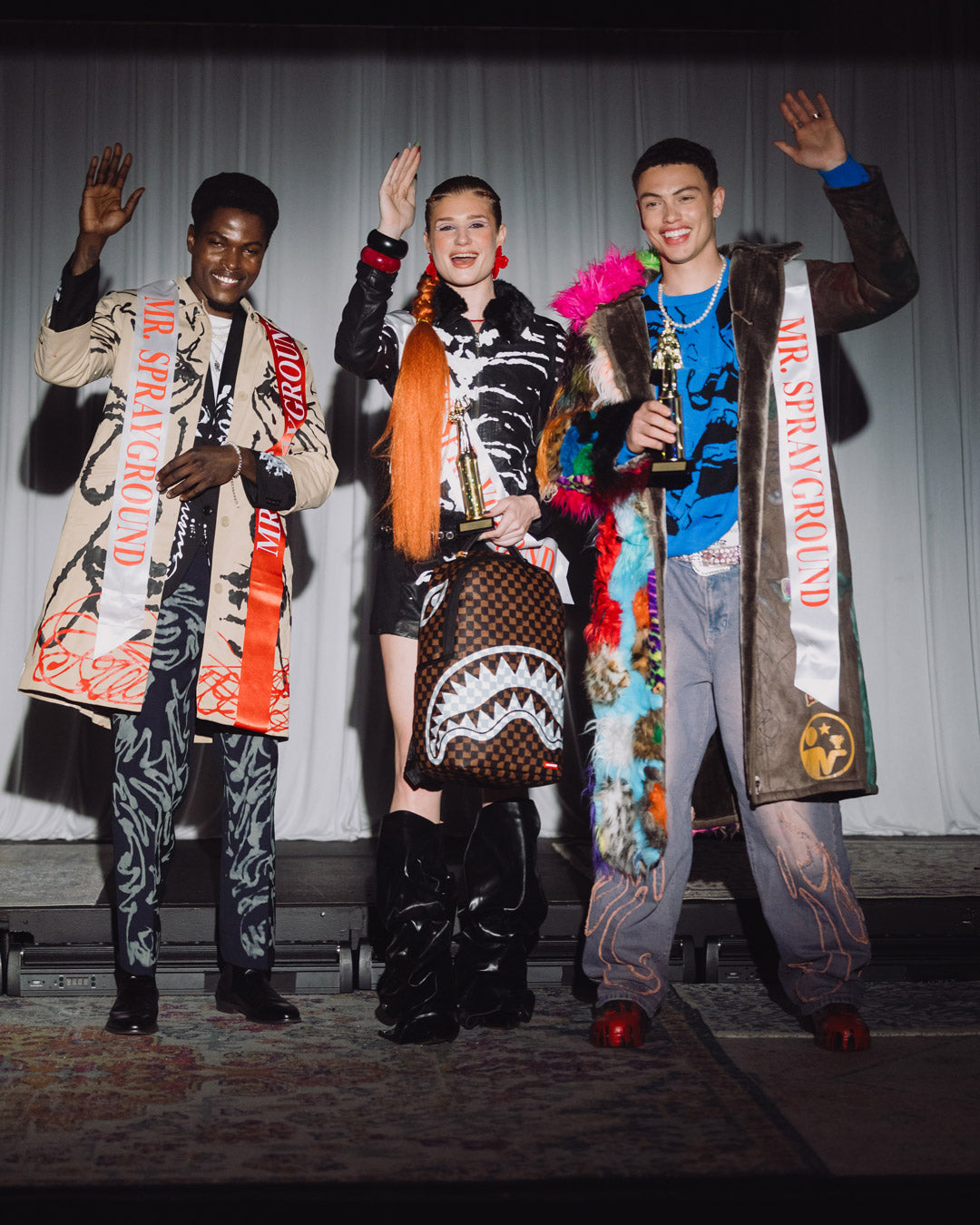 Brown checkered backpack with white fang-style graphic worn by models