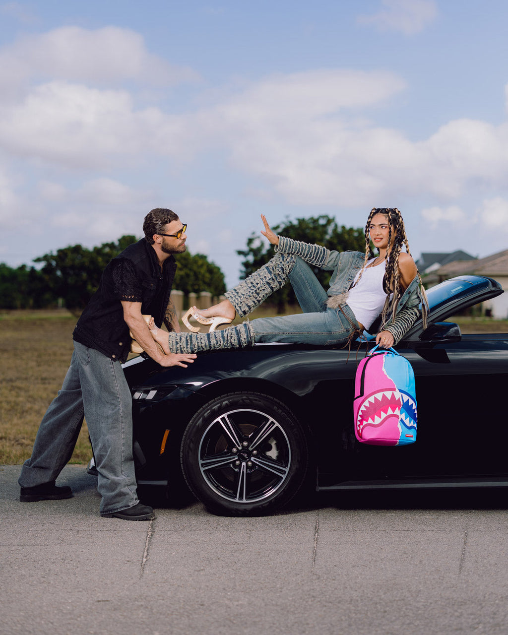 Shark-themed mini backpack resting in car, pink and teal design with top handle