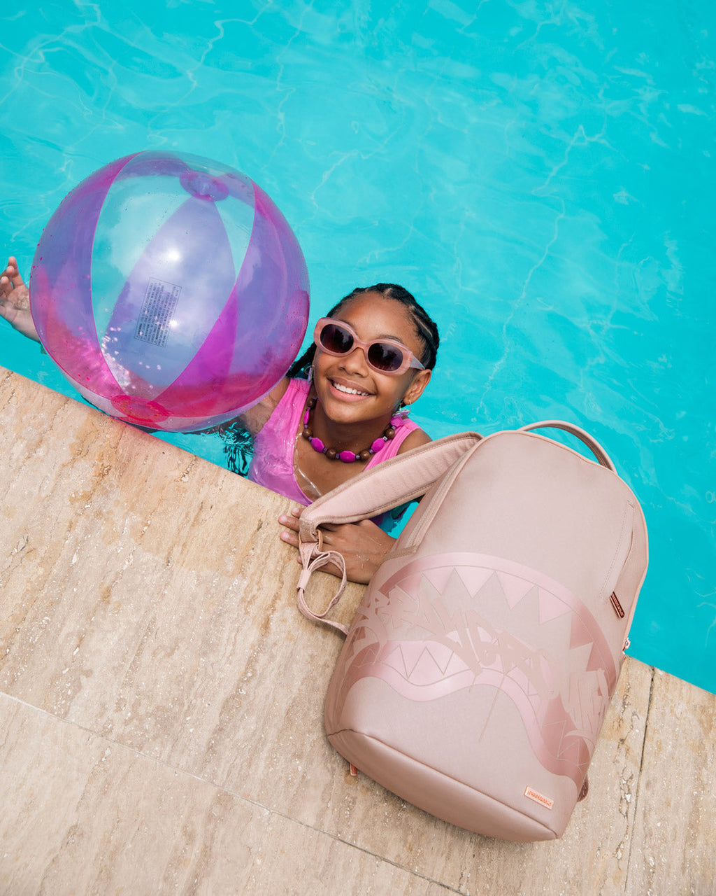 Sprayground rose backpack with shark graphic, side view while held