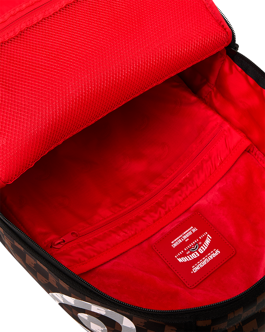 Open backpack showing bright red interior lining and inner logo patch