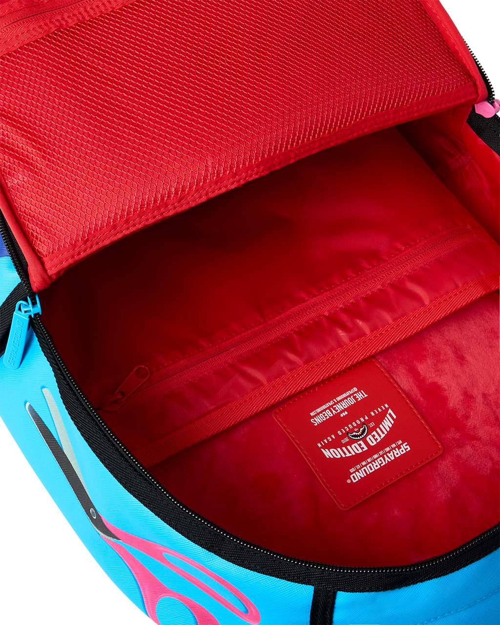 Opened interior of shark-themed mini backpack with red lining and label patch