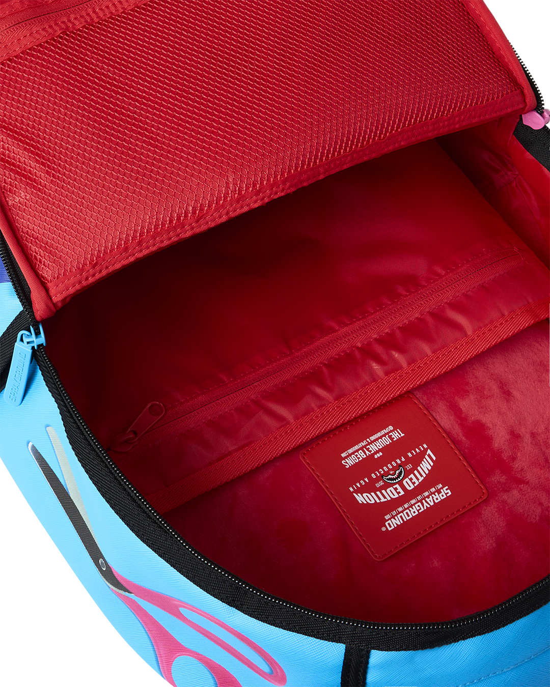 Opened interior of shark-themed mini backpack with red lining and label patch