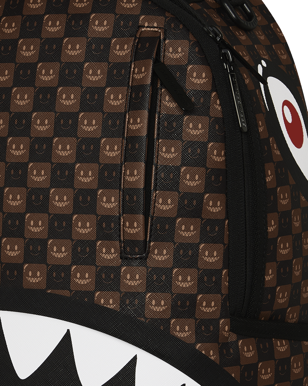 Backpack bag with brown checker pattern and black shark-mouth graphic, front zipper pocket