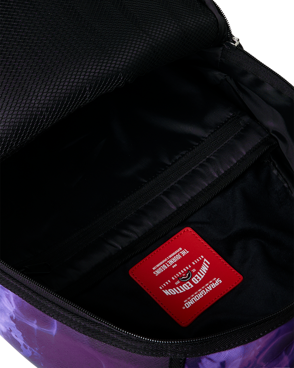 Open backpack bag interior with black lining and red brand patch