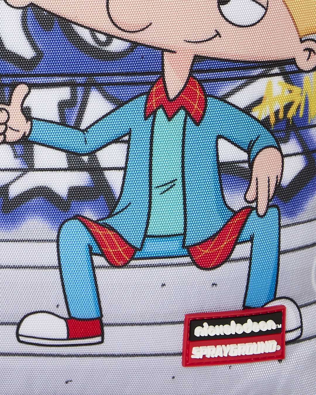 Kids backpack front detail with cartoon boy illustration and Sprayground logo patch