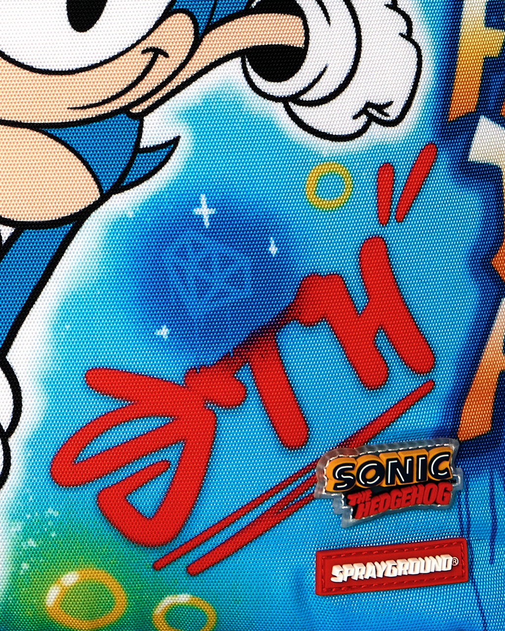 Close-up of blue fabric with “Sonic the Hedgehog” patch and red graffiti text