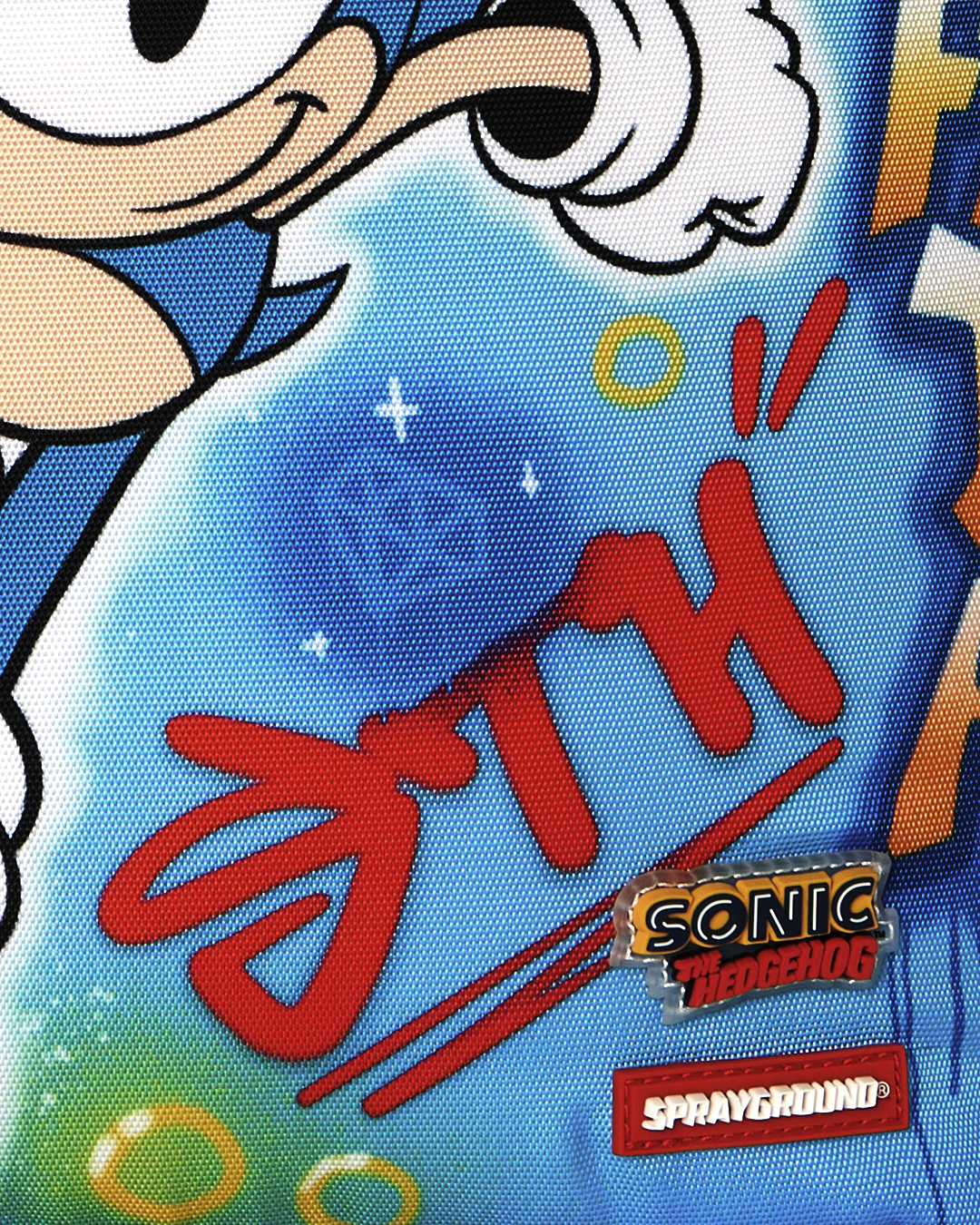 Close-up of blue fabric with “Sonic the Hedgehog” patch and red graffiti text