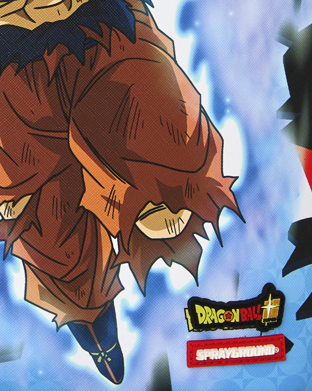 Close-up of Dragon Ball and Sprayground logo patches on blue graphic