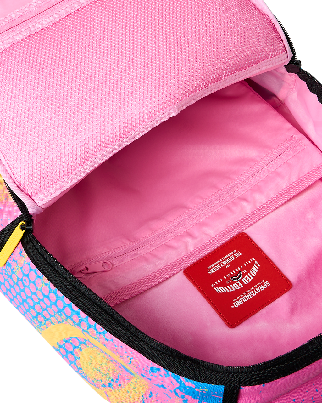 Open interior of pink-lined backpack with zip pocket and red brand label