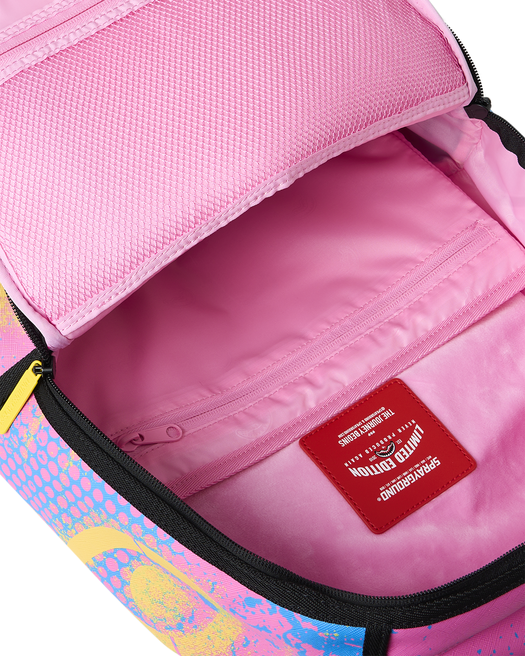 Open interior of pink-lined backpack with zip pocket and red brand label