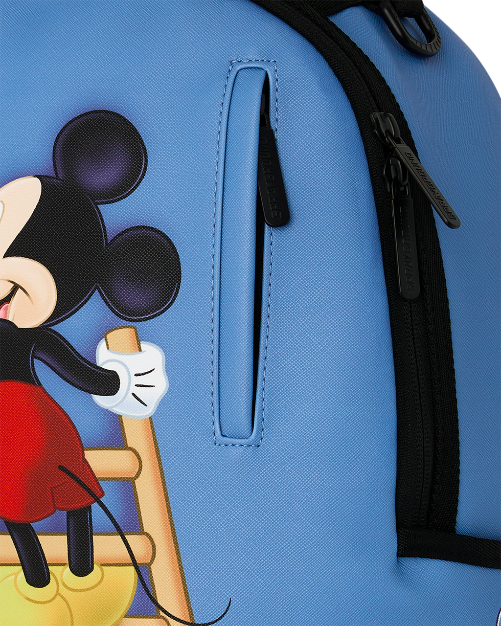 Blue backpack side pocket detail with black zipper pull and stitched handle tab