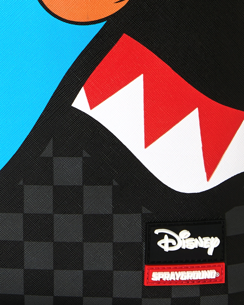 Close-up of Disney and Sprayground brand patch on black checker backpack
