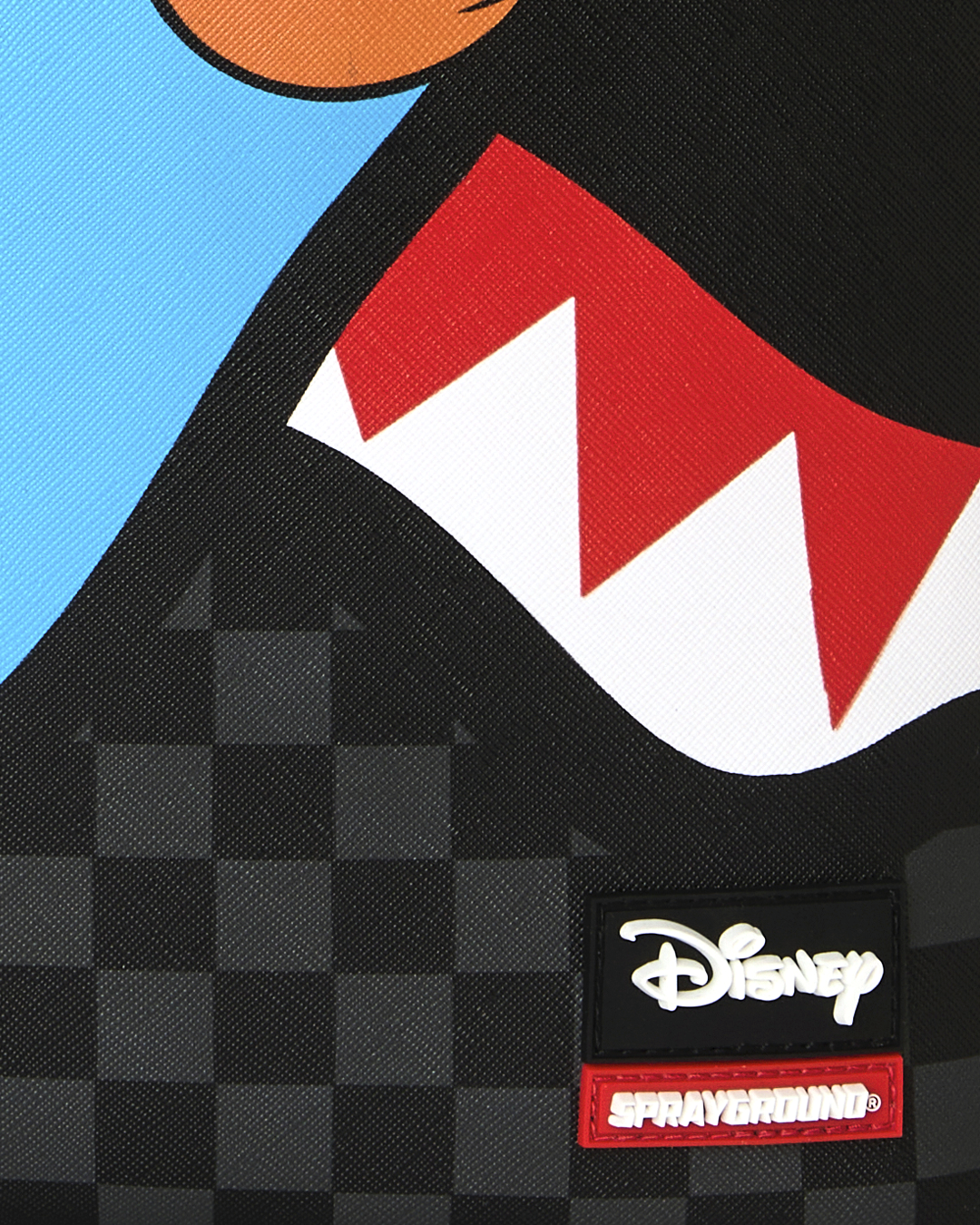 Close-up of Disney and Sprayground brand patch on black checker backpack