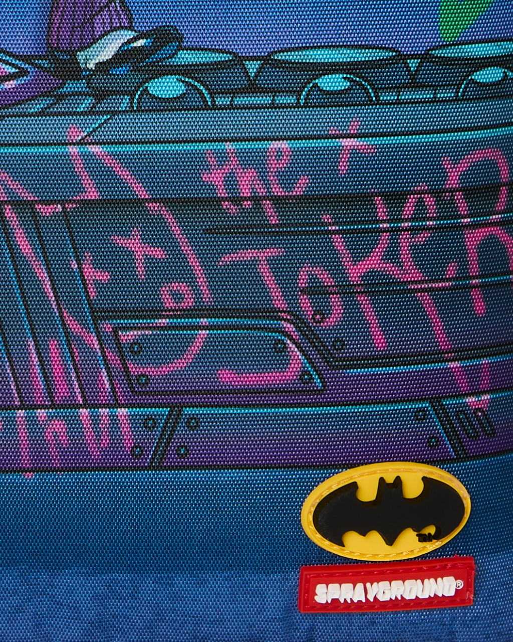 Close-up of Batman logo and red brand patch on blue Joker graphic