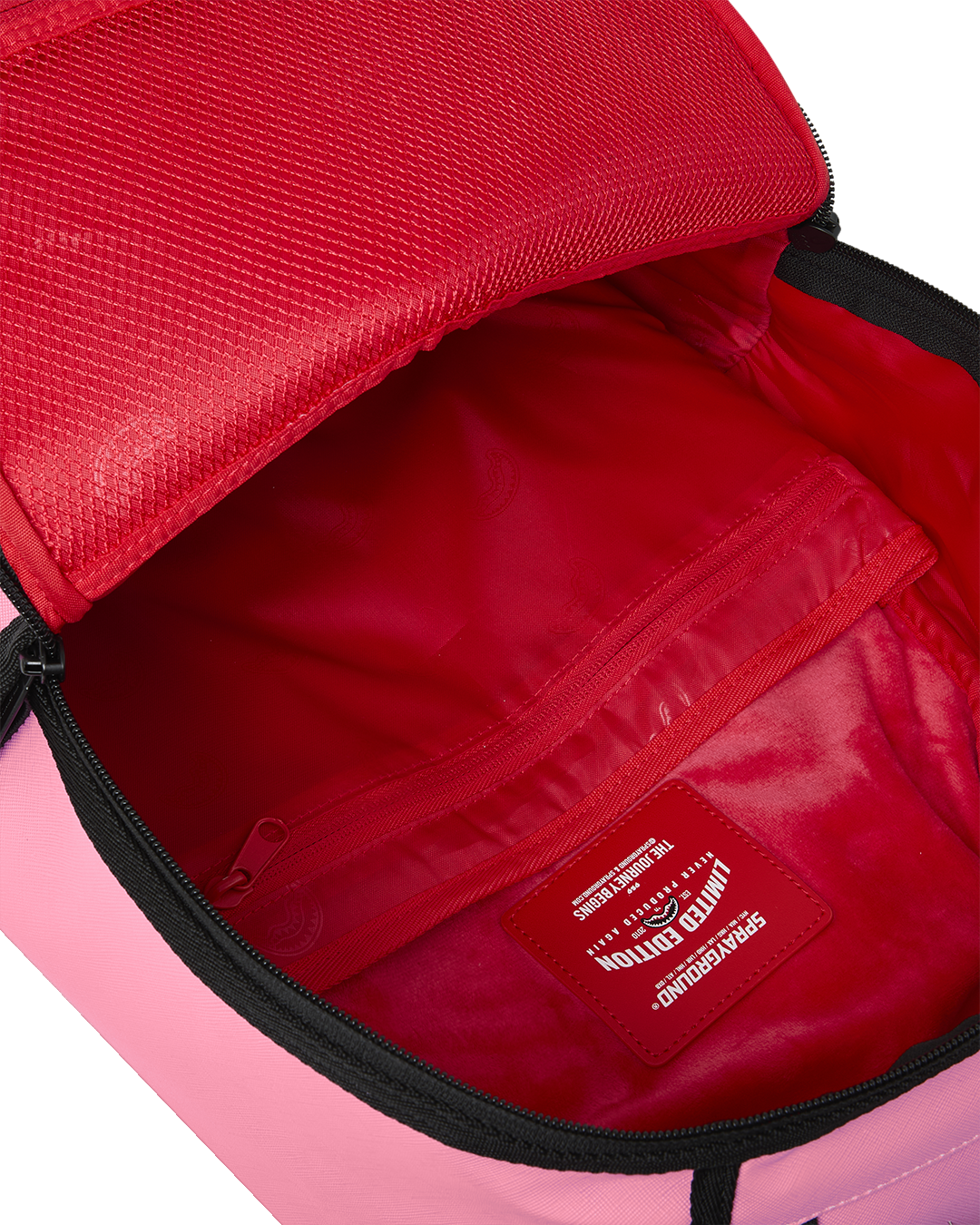 Pink backpack with red interior, zip pocket, and stitched brand patch