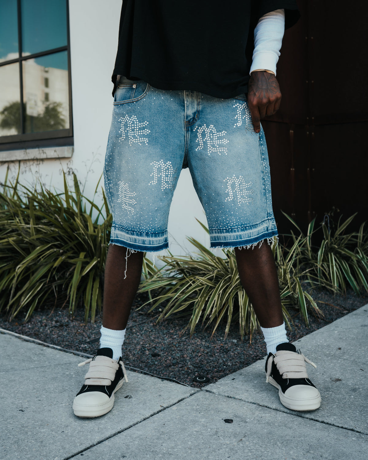 Blue denim shorts with rhinestone graphic on each thigh and frayed cuff