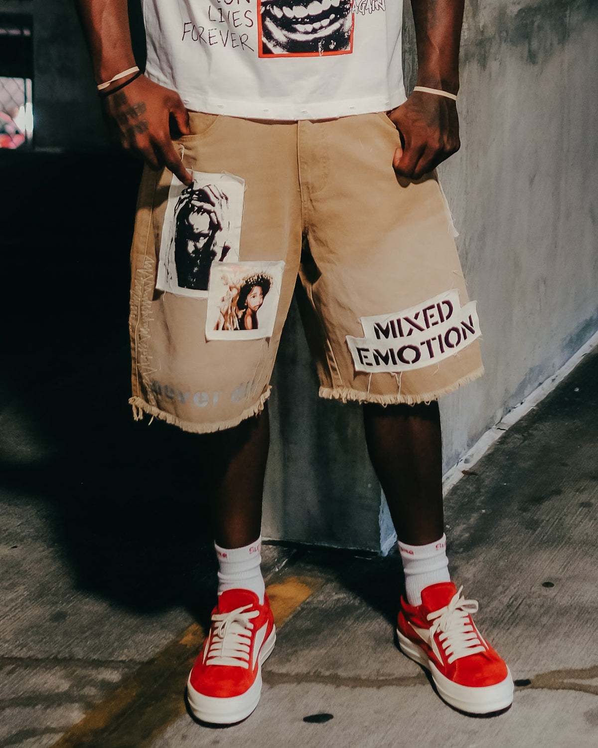 Men's brown carpenter shorts worn by model with graphic front patches and frayed hem