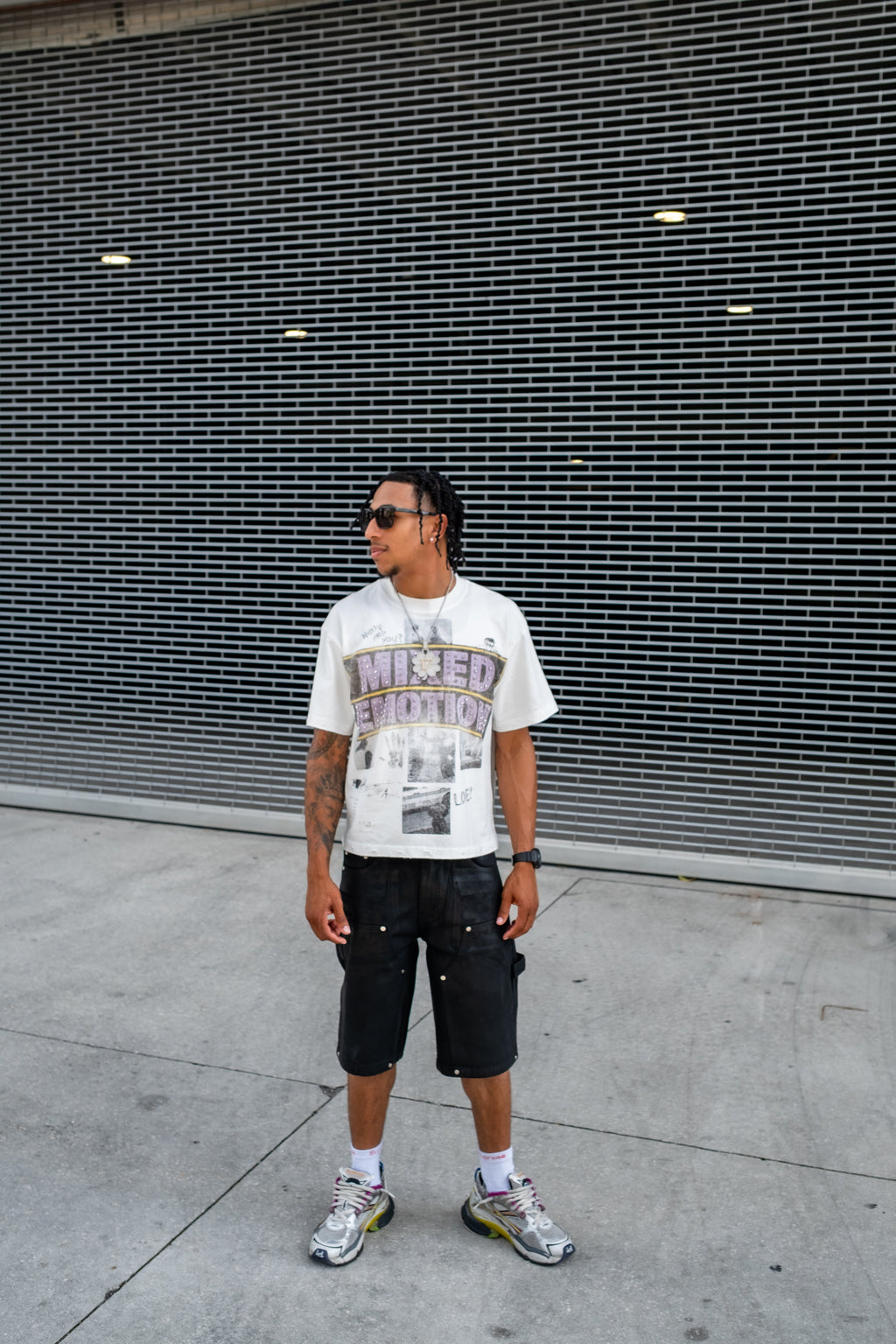 Men's white graphic T-shirt worn with black shorts and sneakers, full-body view