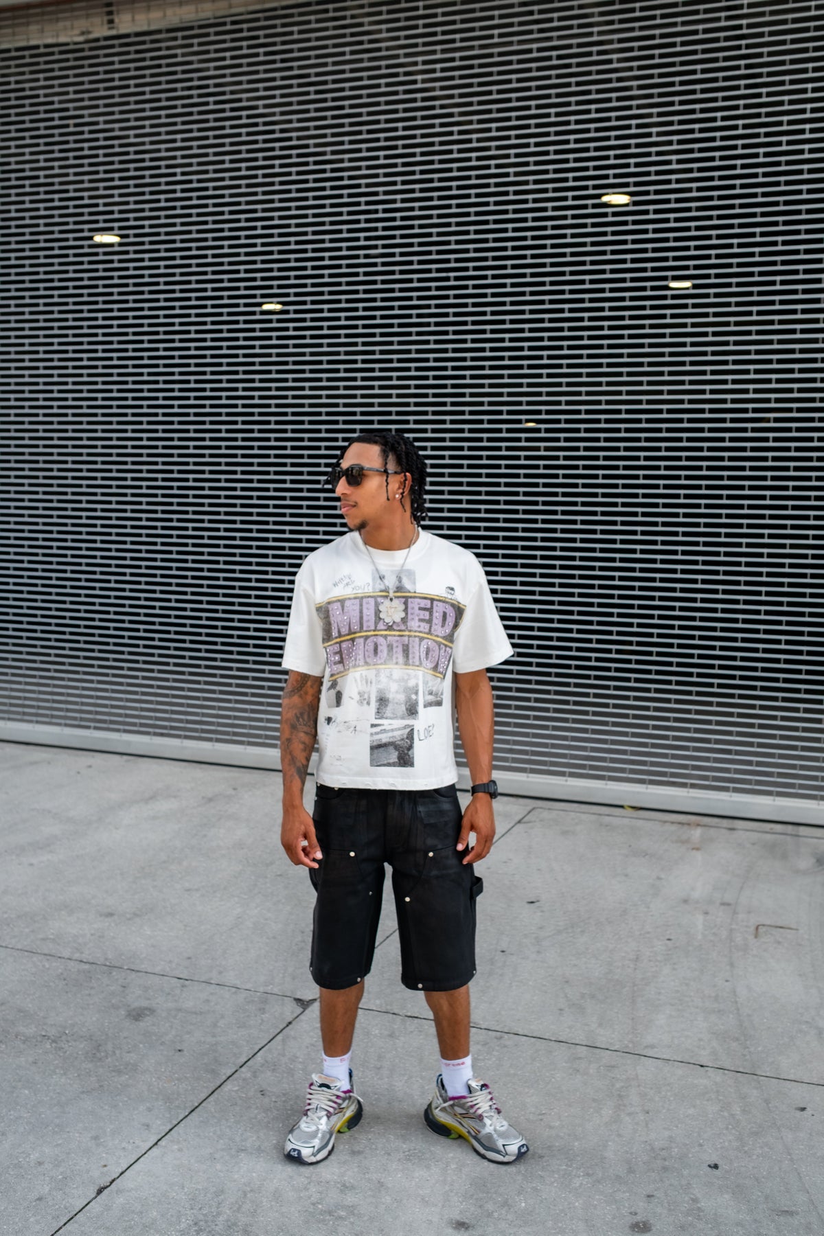 Men's white graphic T-shirt worn with black shorts and sneakers, full-body view