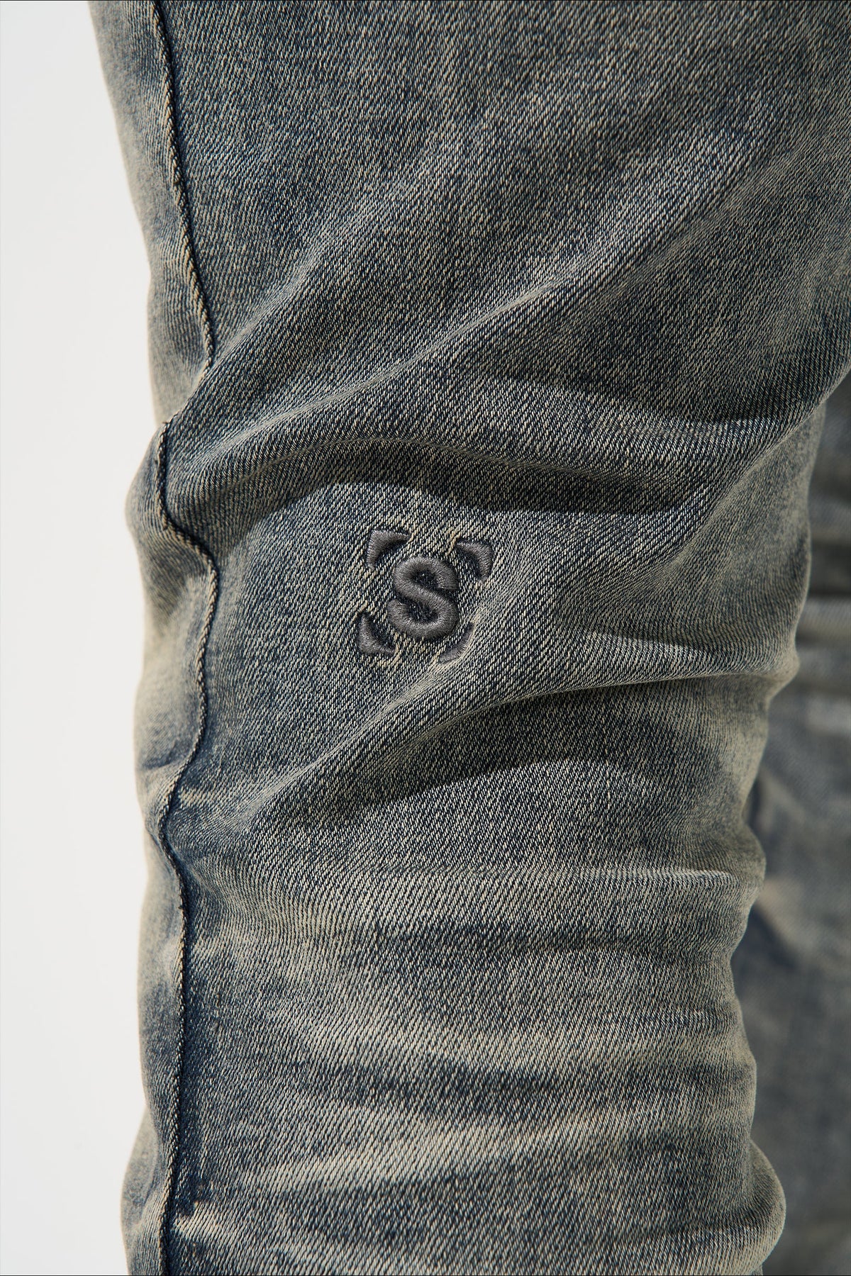 Men's gunmetal jeans with embossed logo patch on thigh and stitched panel