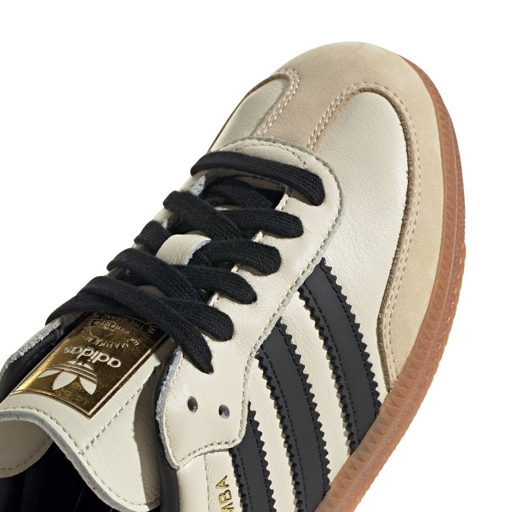 Adidas Samba OG women's shoe close-up: cream leather upper with black laces and stitched stripes.