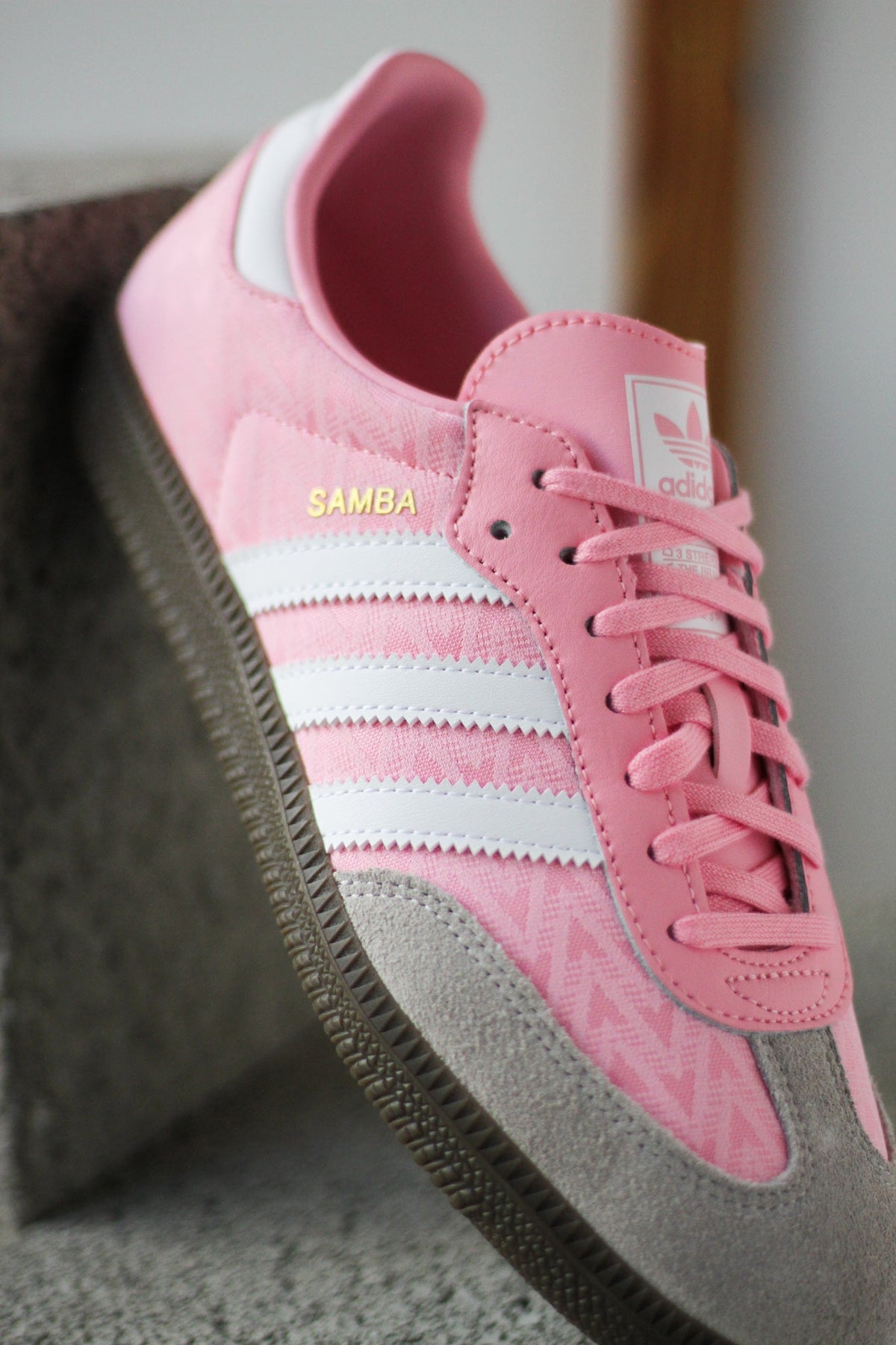 Kids' pink adidas Samba sneakers close-up with white stripes and pink lace-up
