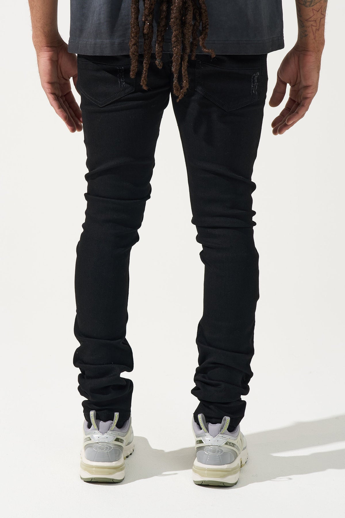 Men's black denim jeans with faded knee wear and slim tapered legs