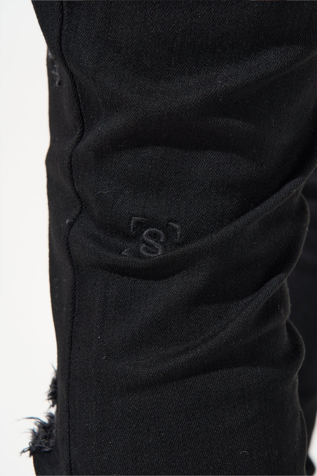 Jet black jeans with embroidered logo on side seam and frayed hem