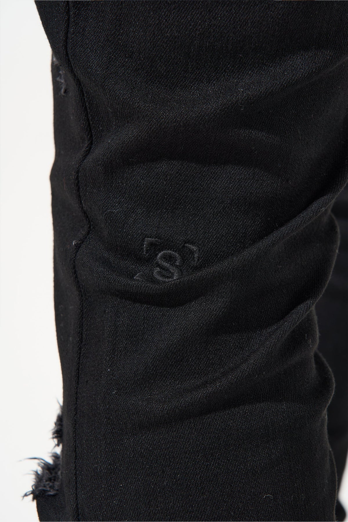 Jet black jeans with embroidered logo on side seam and frayed hem