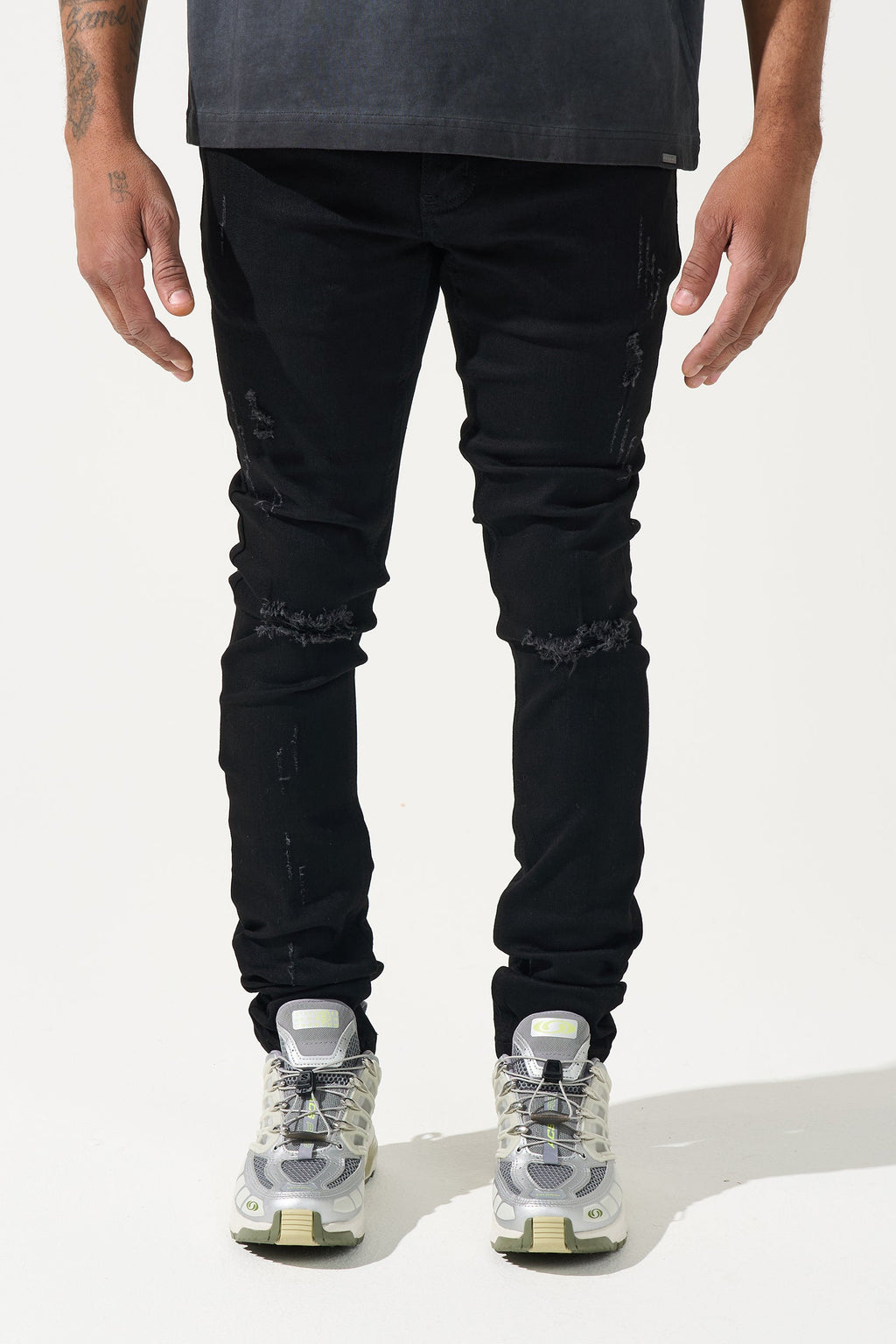 Men's jet-black jeans with ripped detailing at knees and slim tapered fit