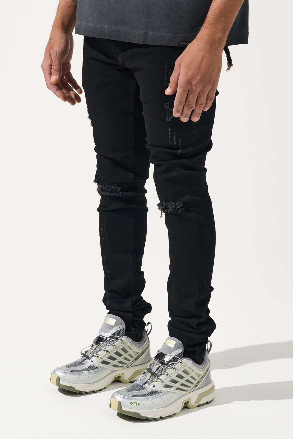 Men's black distressed jeans with scuffed patches on knees and fitted cuffs