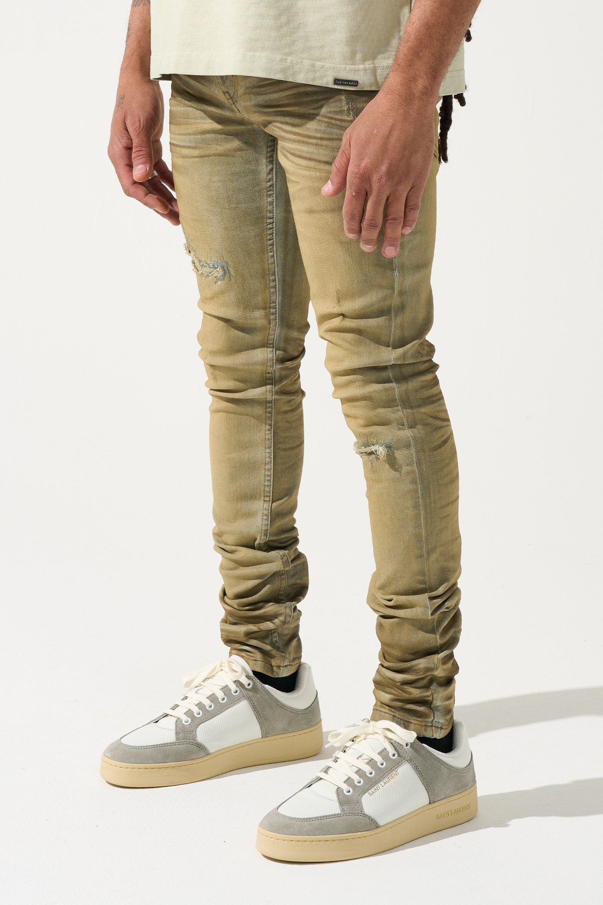 Men's skinny jeans in muted olive with heavy dirty wash, ankle bunching, and knee rips