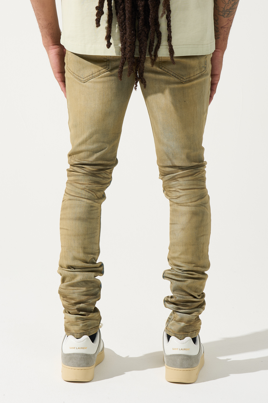 Men's distressed skinny jeans in muted olive with back pockets and faded dirty wash at cuffs
