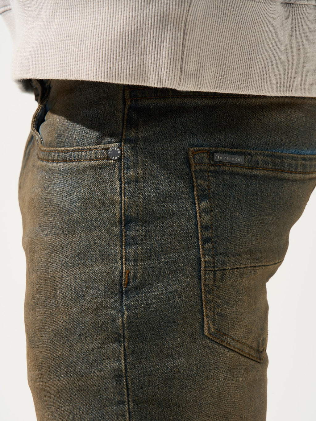 Earth-brown denim jeans close-up of front pocket stitching and seams.