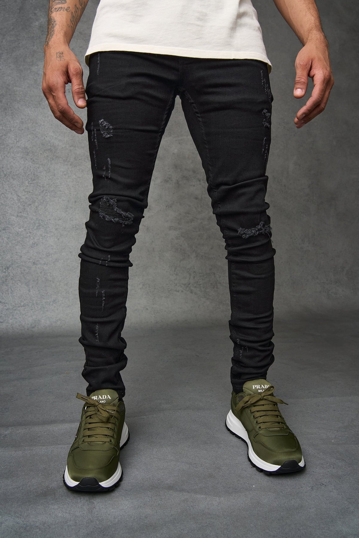 Men's black distressed jeans with knee scuffs and tapered leg styling