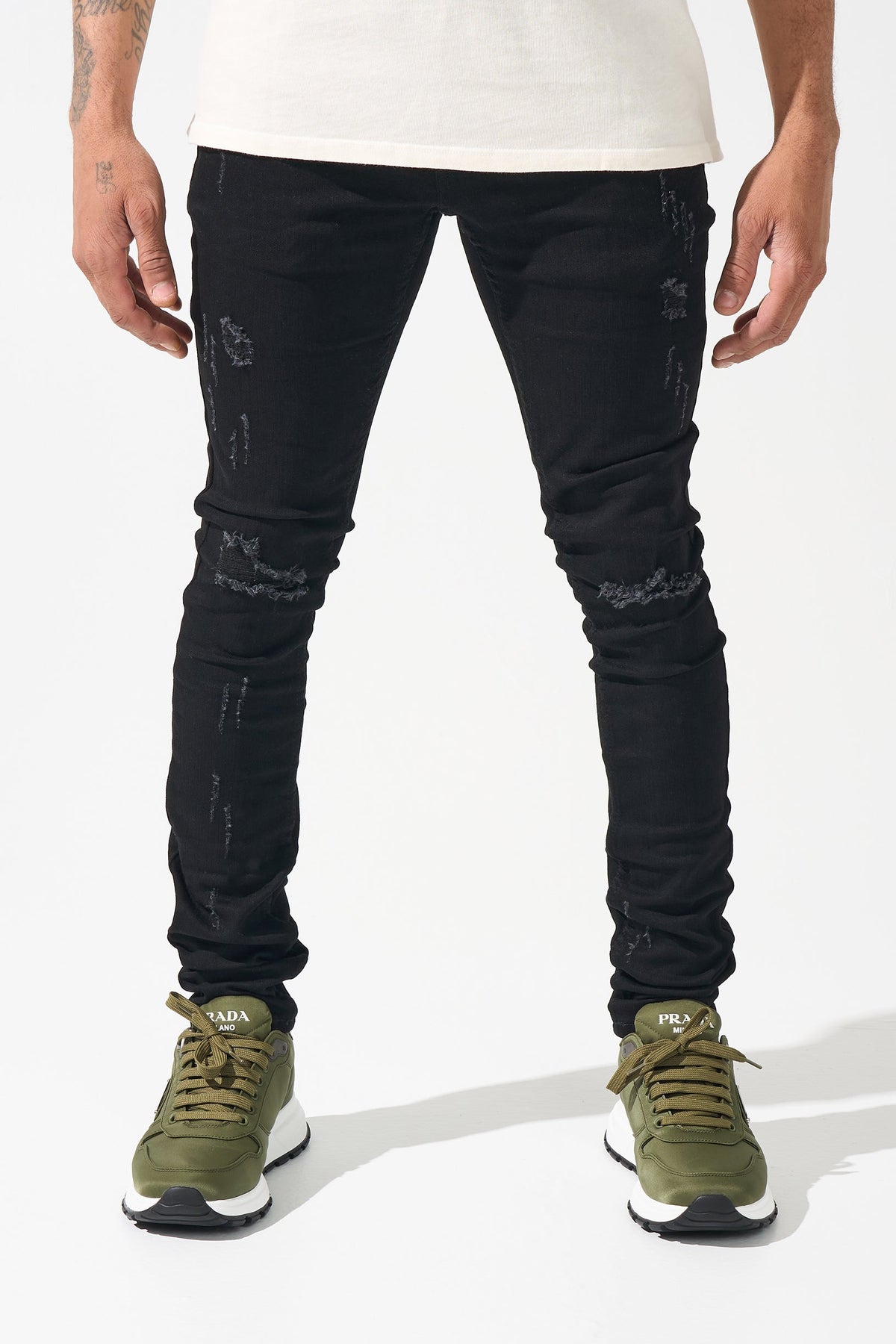 Men's black jeans with distressed knee areas and narrow tapered leg fit
