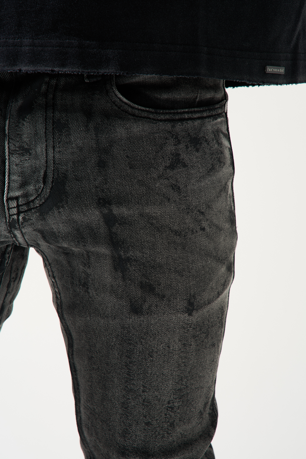 Charcoal washed denim jeans close-up, worn pattern and seam detail.