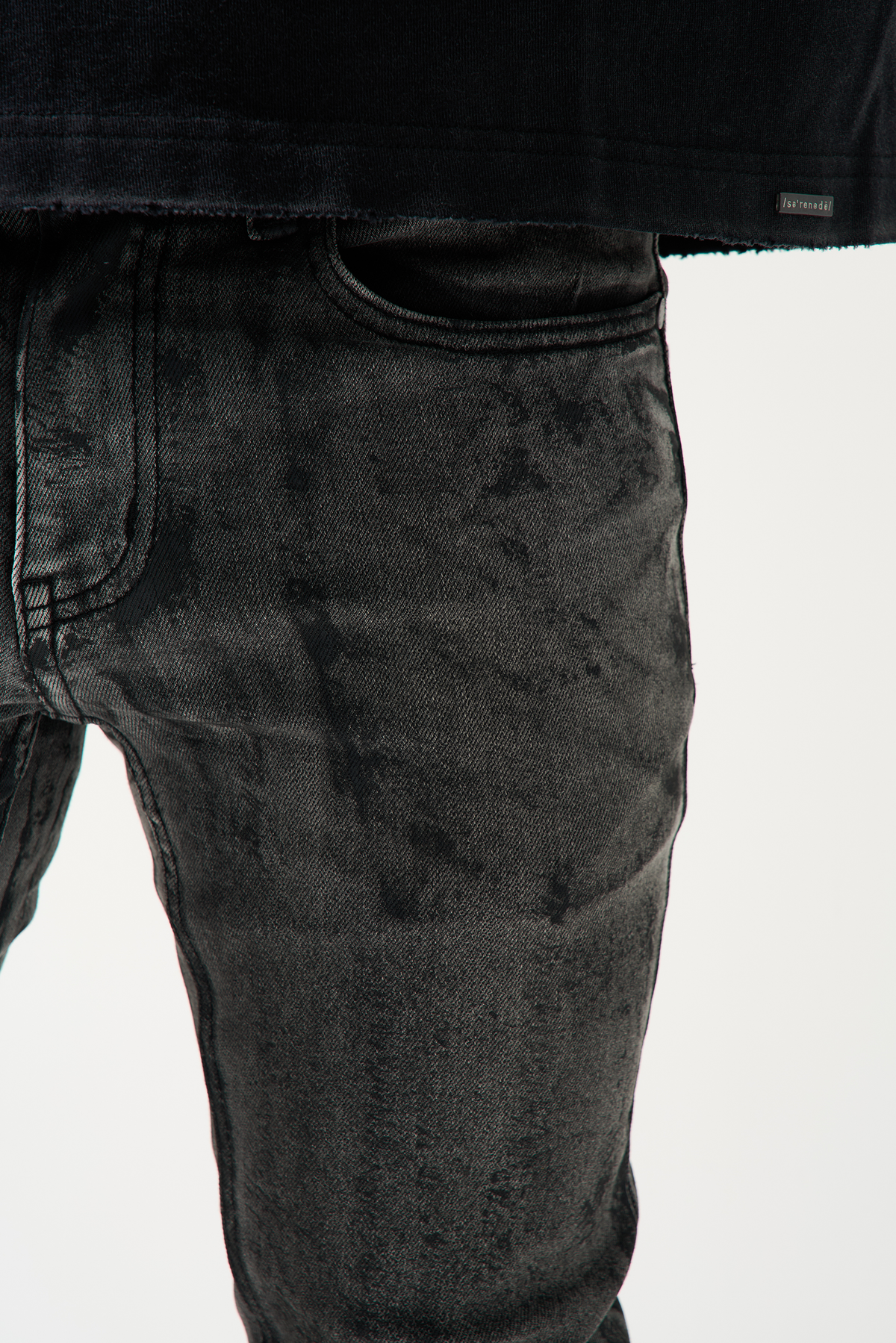 Charcoal washed denim jeans close-up, worn pattern and seam detail.