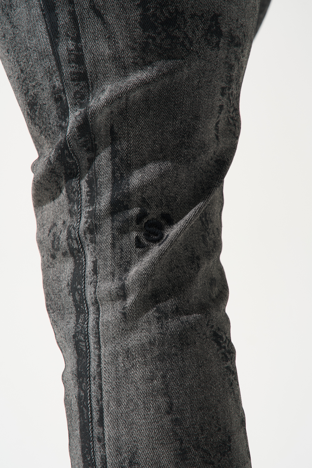 Charcoal washed denim jeans close-up, pocket seam and distressed texture.