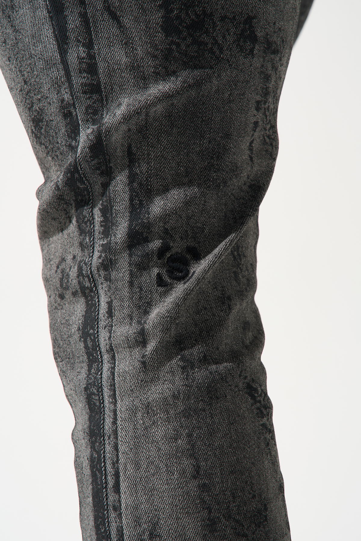 Charcoal washed denim jeans close-up, pocket seam and distressed texture.