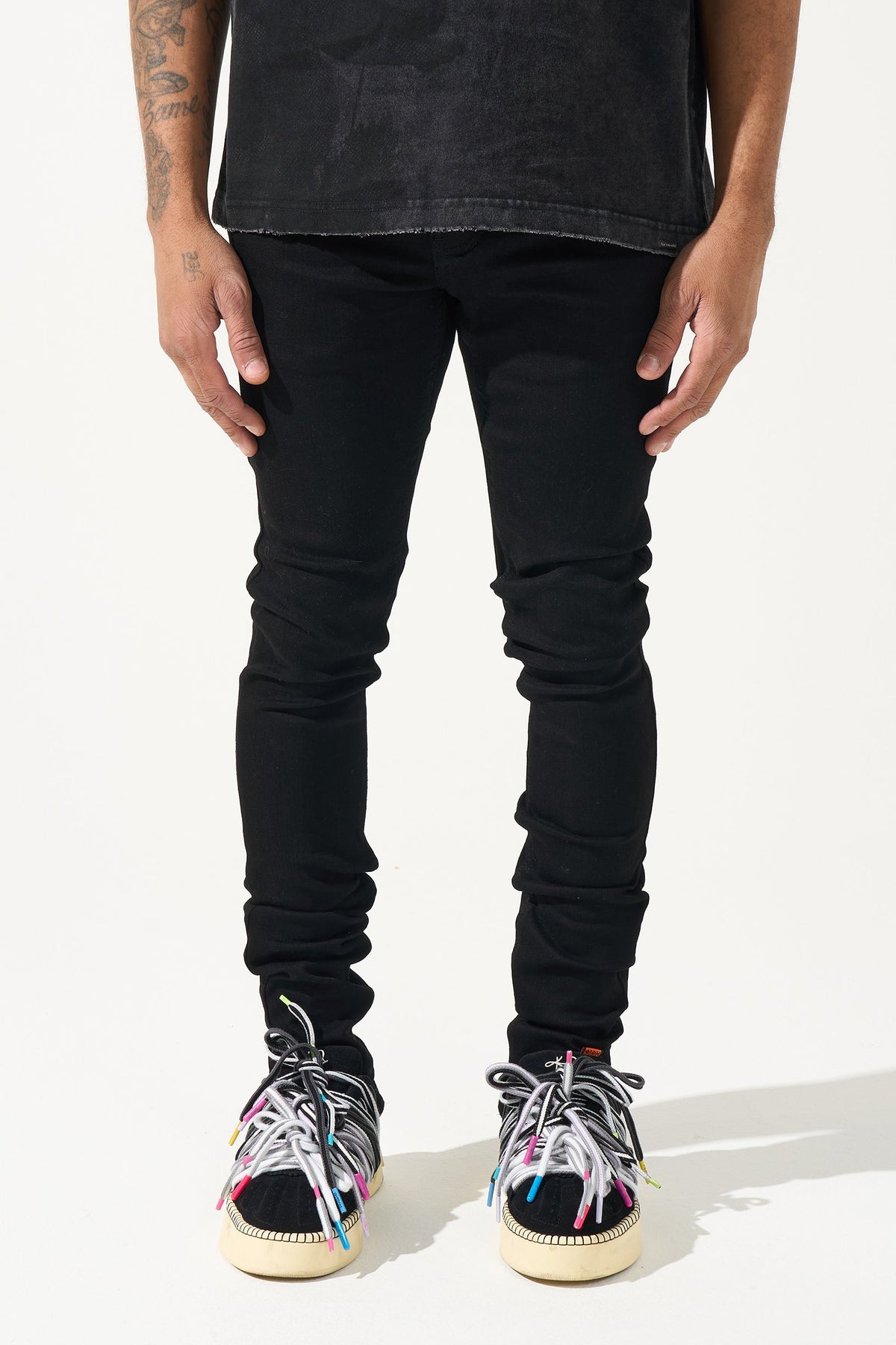 Men's black slim-fit jeans with tapered legs and ruched knee panels