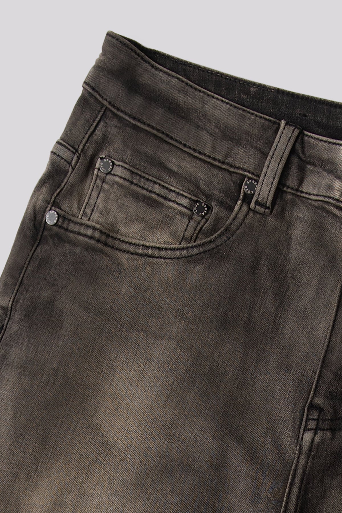 Men's olive denim jeans close-up of waistband, button, and pocket stitching.
