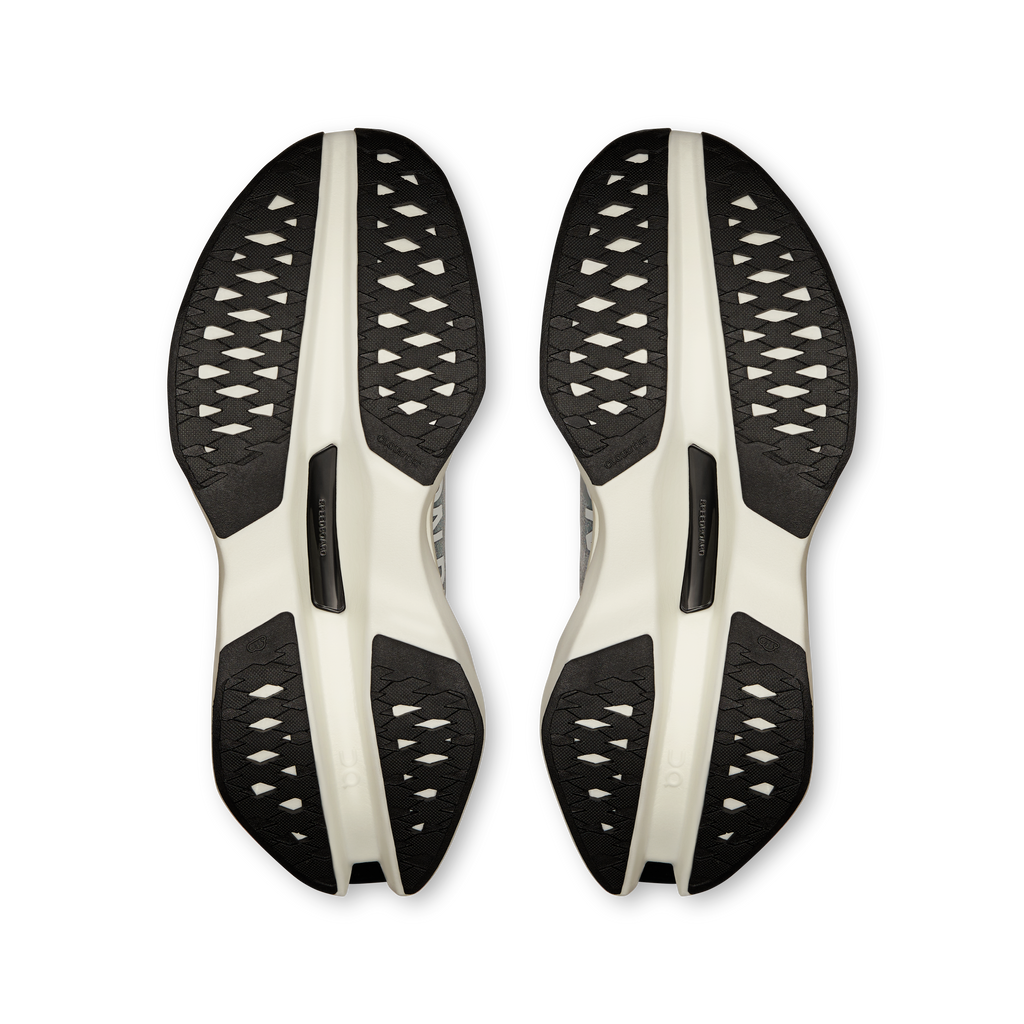 Pair of On running shoe outsoles with black tread pattern and light midsole pods