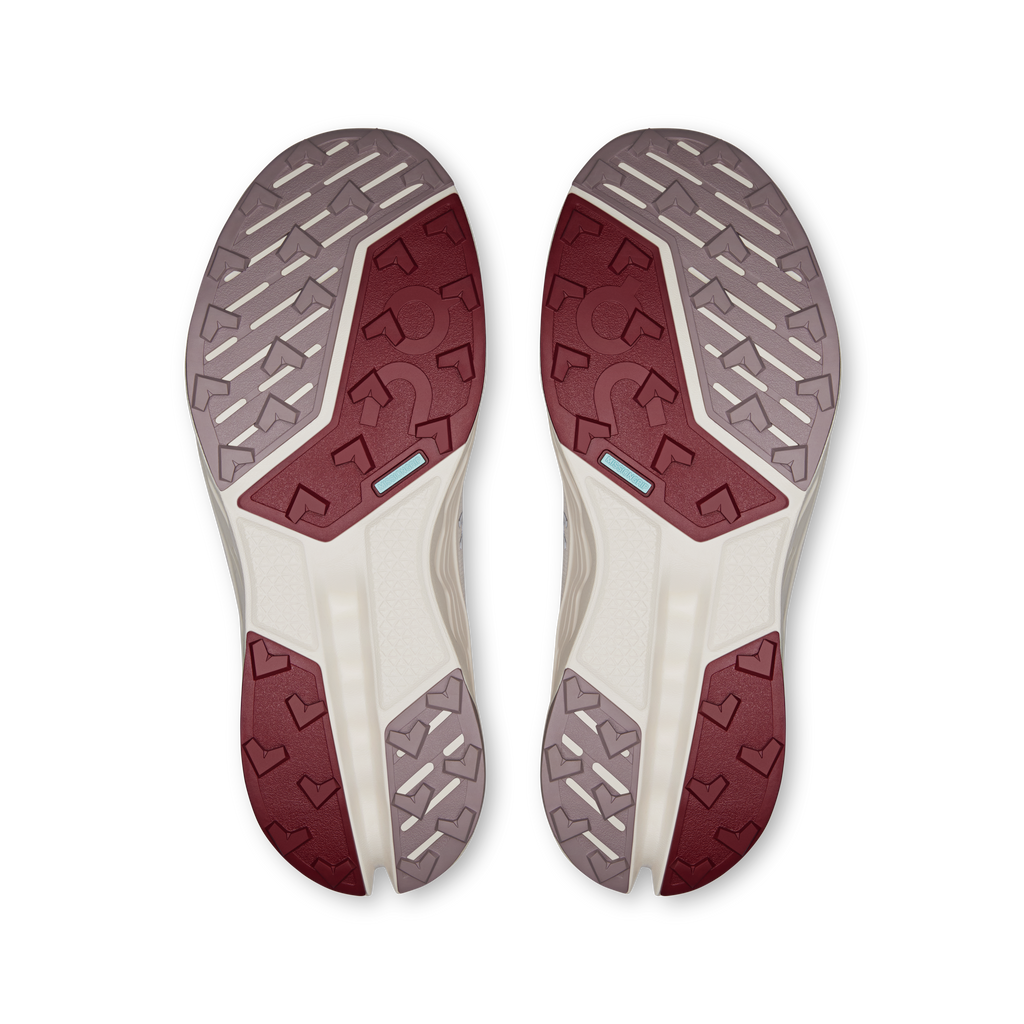Pair of trail shoe outsoles with patterned rubber grips and burgundy traction panels
