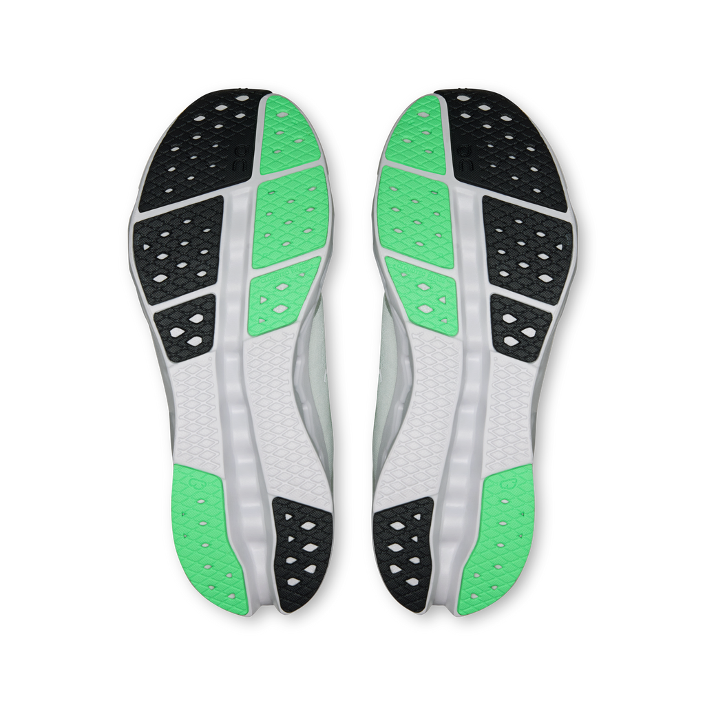 Shoe outsoles with green tread inserts, black traction pods, and white cushioning