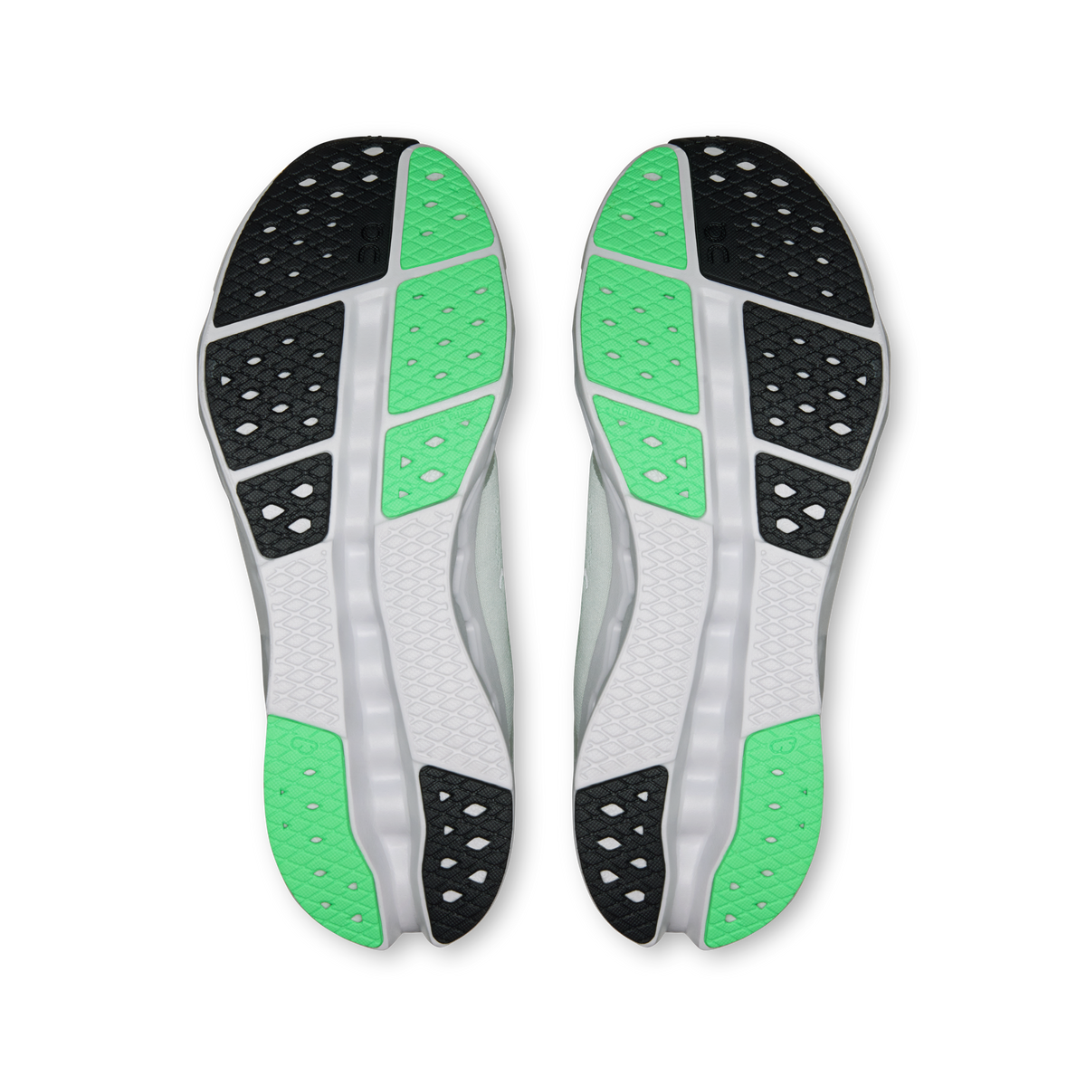 Shoe outsoles with green tread inserts, black traction pods, and white cushioning